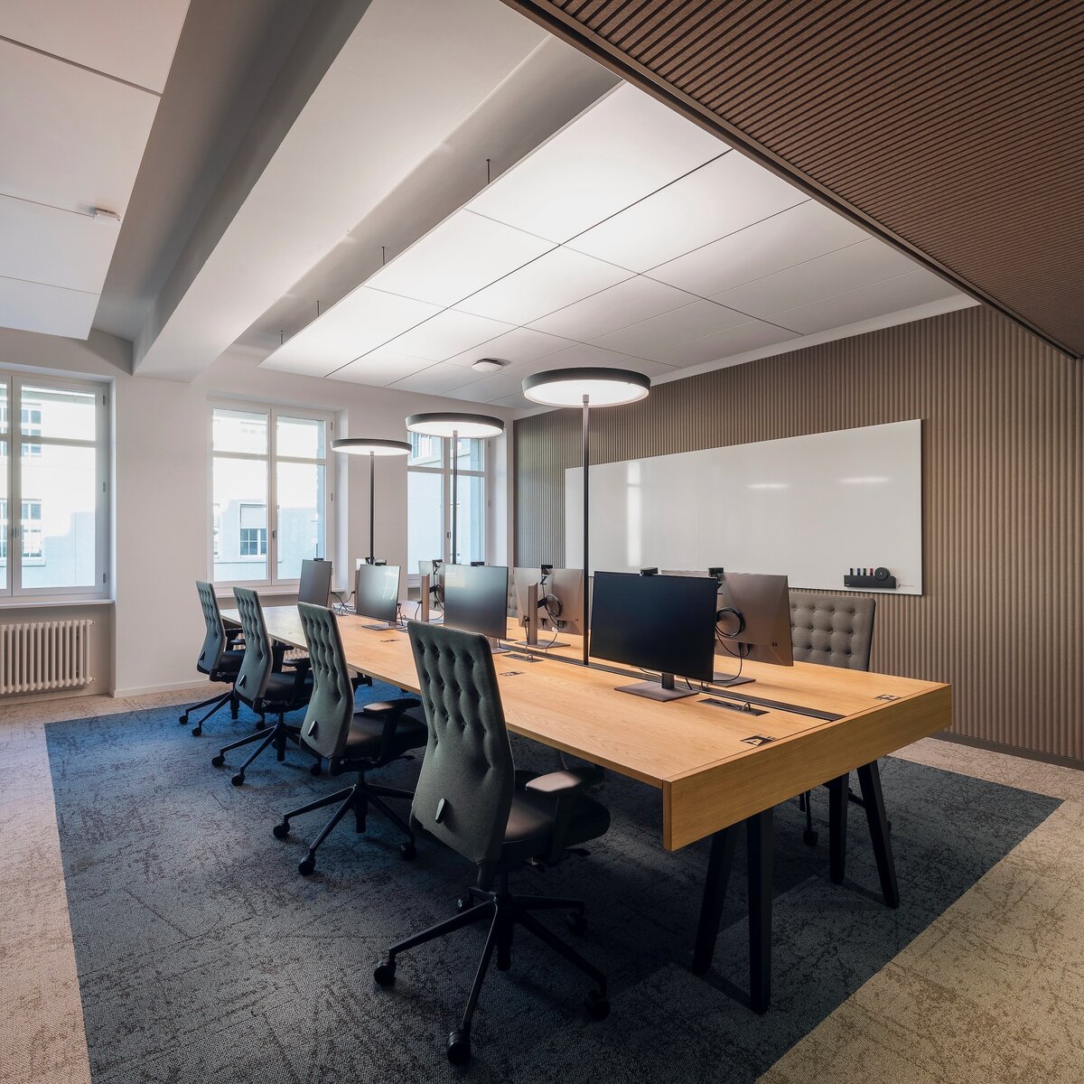 © Fotos: Peter Würmli © Evolution Design Moderne Büroinsel mit acht Arbeitsplätzen in hell gestaltetem Raum mit Holzoptik und warmem Ambiente | © Fotos: Peter Würmli © Evolution Design