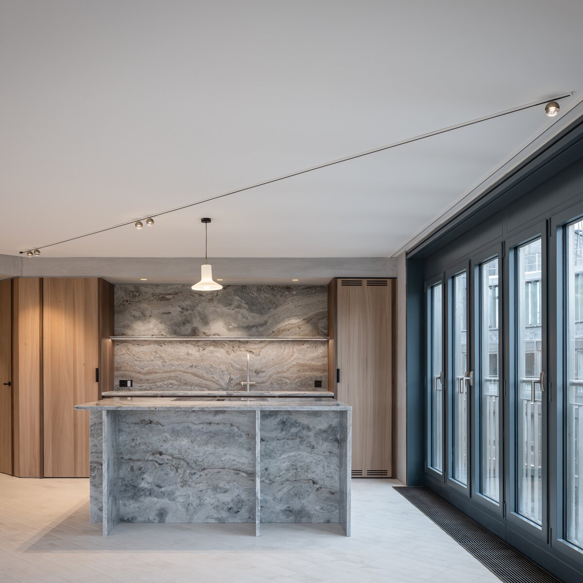 © © www.Lindner-Group.com Moderner Küchenbereich mit heller Marmor-Kücheninsel, Fensterfront und hochwertiger Holzvertäfelung in stilvollem Innenraum | © © www.Lindner-Group.com