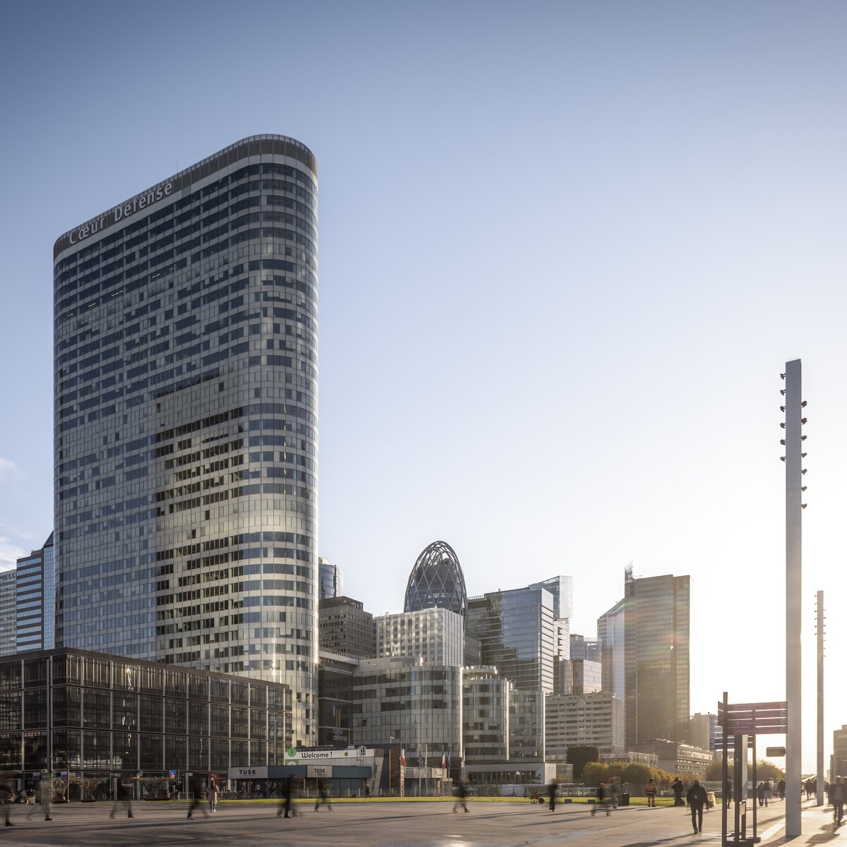 © © www.Lindner-Group.com Außenansicht des Bürokomplexes Cœur Défense in Paris mit Vorplatz, umliegenden Hochhäusern, Passanten und tief stehender Sonne | © © www.Lindner-Group.com